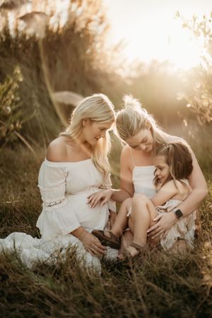 Family shares tender moment together outdoors during golden hour portrait session.
