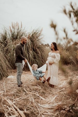 Playful interactions between family members amidst dried grass and natural scenery.