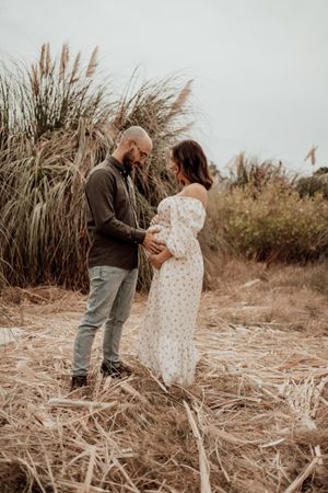 Family photoshoot in a rustic outdoor setting with tall pampas grass in the background.