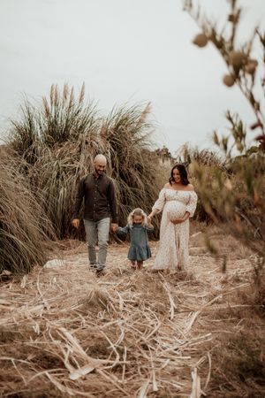 Family walking together through a natural landscape with tall grass and muted tones.