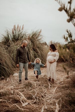 Candid family moments captured in a natural setting with dried grass and soft lighting.