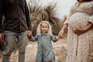 Intimate family portrait session with coordinated outfits against a natural backdrop.