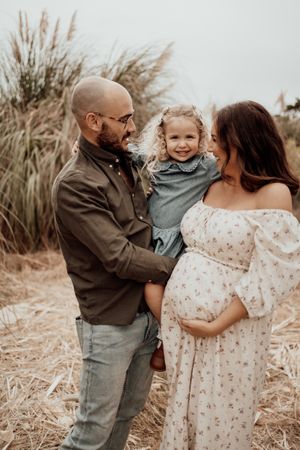 Sweet family interactions captured in warm sepia tones among dried grass.