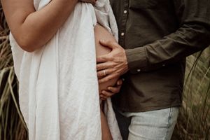 Close-up of couple's hands cradling pregnant belly in intimate moment.
