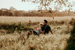 Family enjoying a playful moment together in a rustic outdoor field during golden hour.