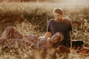 Family playing together in a golden sunset field with tall grass and warm lighting.