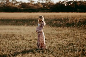 Family members stand in a golden field during sunset creating a dreamy outdoor scene.