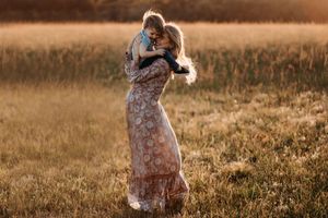 Family sharing intimate moments in a sun-drenched field during golden hour.