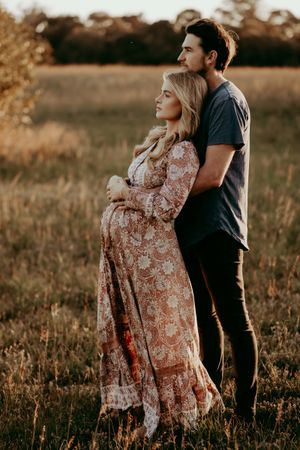 A tender moment between two people in a floral dress and casual wear during sunset.