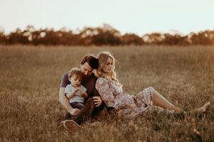 A family relaxes together in a golden meadow during sunset.