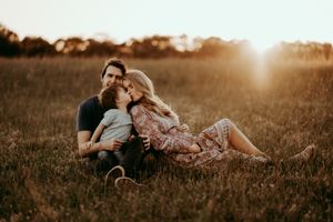 A family sits together in a sun-drenched field during golden hour.