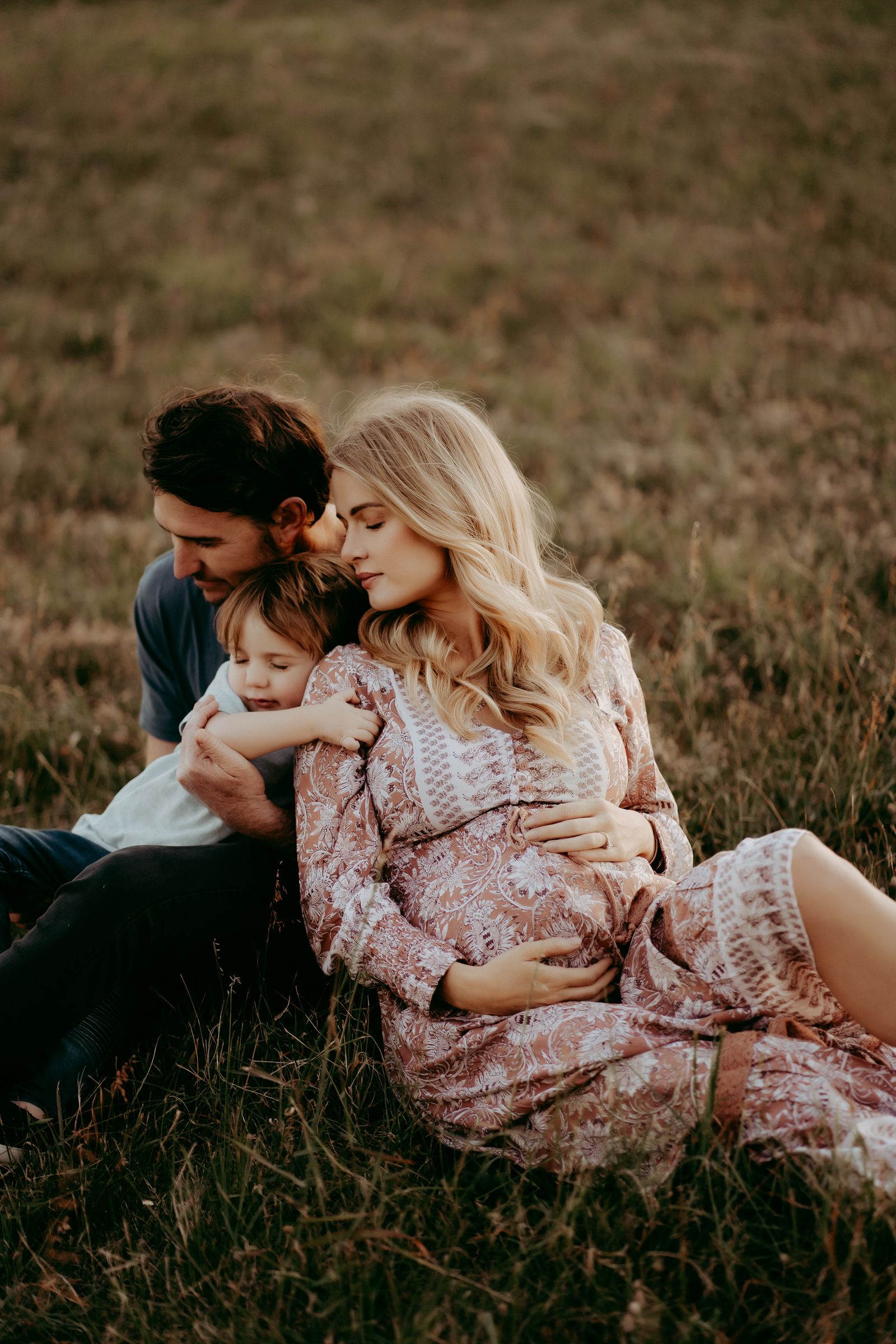 An intimate family moment captured while resting in a rustic field at sunset.