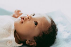 Close-up portrait of a newborn baby lying on light blue blanket showing different expressions and angles.