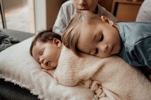 Child resting with soft cream blanket in natural light.