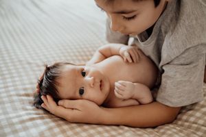 A tender moment of connection as a child rests on bedding with warm muted lighting.