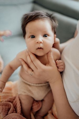Close up of an alert baby with wide eyes looking directly at camera.