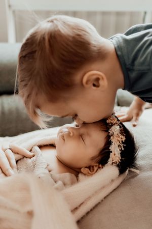 Gentle kiss shared with sleeping baby wearing delicate floral headpiece.