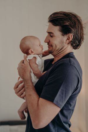 Tender moment between parent and infant in soft natural lighting.