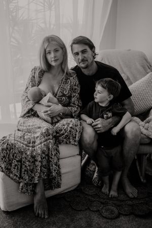 Family sitting together on couch with newborn in cozy indoor setting.
