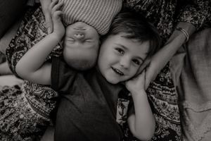 Black and white portrait of siblings laying down together.