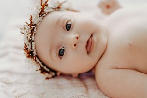 Close-up portrait of infant lying down with delicate floral crown.