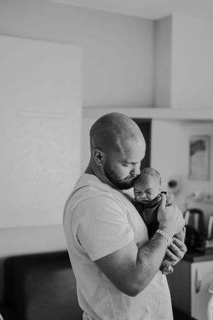 Black and white series showing emotional moments between parent and newborn in home setting.