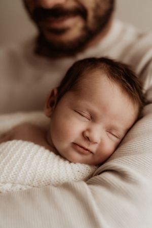 Close-up of peaceful sleeping newborn with soft features against white fabric.