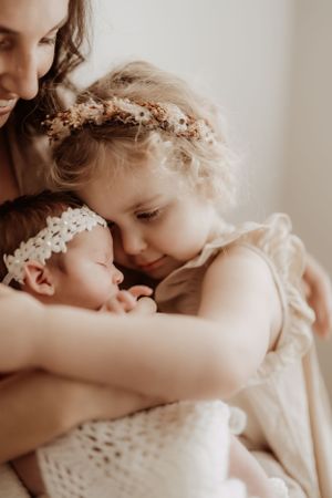 Sweet toddler wearing floral crown embracing parent in dreamy setting.