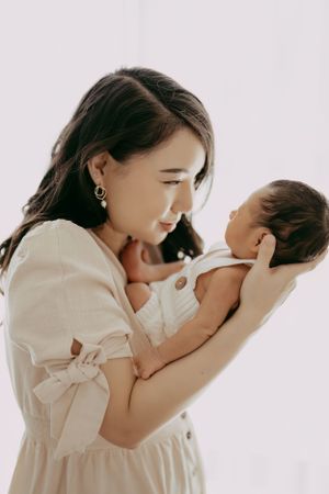 A tender moment between parent and baby in soft, natural lighting against a white background.