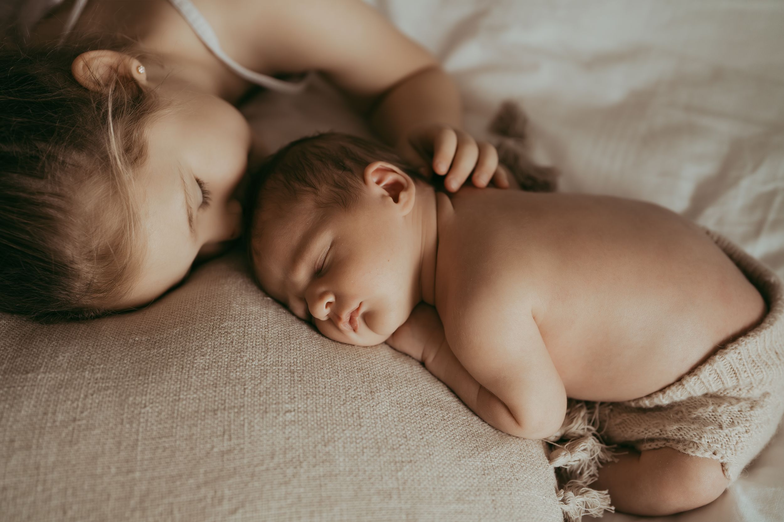 Peaceful sleeping newborn resting on soft white bedding.