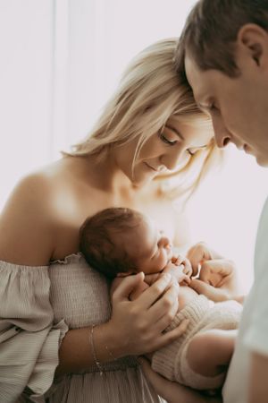 Intimate newborn photography session with parents in soft lighting.