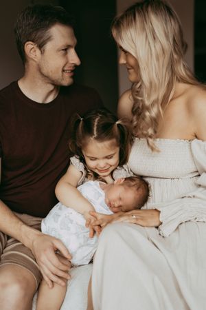 Indoor family portrait showing tender moments between parents and children in neutral tones.