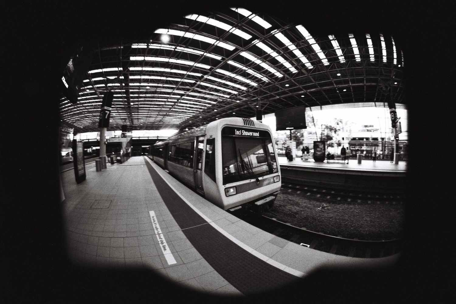 Modern subway train at curved platform station captured through fisheye lens.