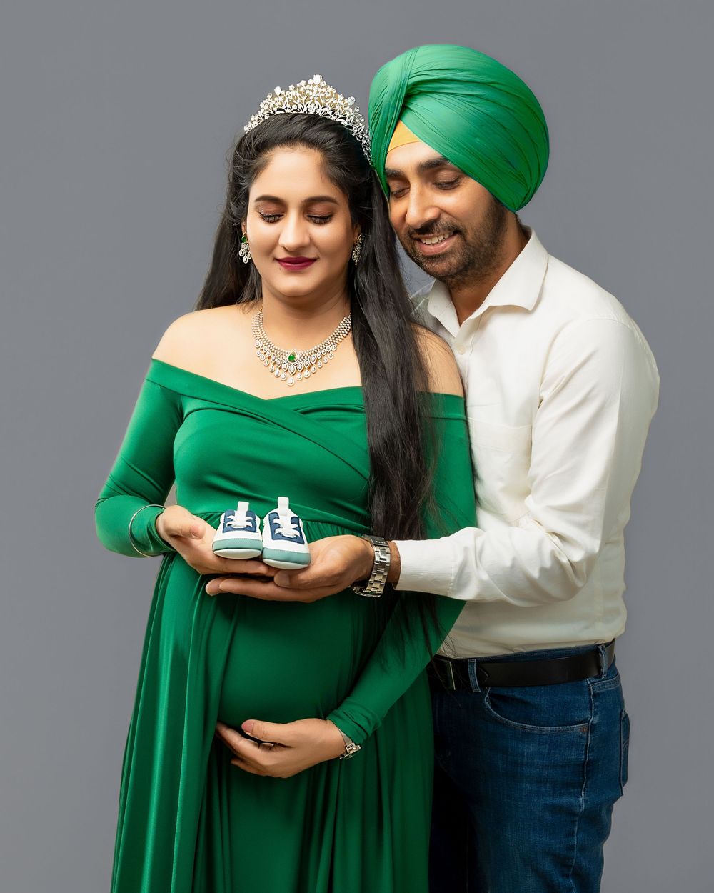 Couple in green dress and white turban share intimate moments while looking at a mobile phone in studio portraits.