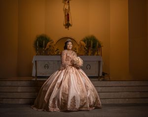 Ornate champagne-colored ball gown photographed in front of an altar with warm lighting.
