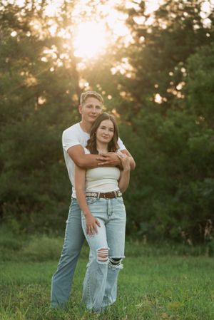Romantic sunset portrait of couple embracing in grassy field.