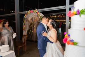 Wedding couple sharing intimate moment near decorated arch and wedding cake.