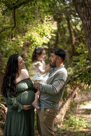An outdoor family photo in a wooded setting with natural lighting.
