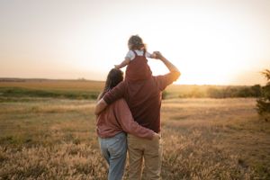 Couple embracing while watching sunset in golden field.