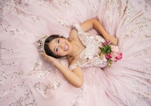 Overhead portrait of person in embellished pink princess gown holding fresh flowers.
