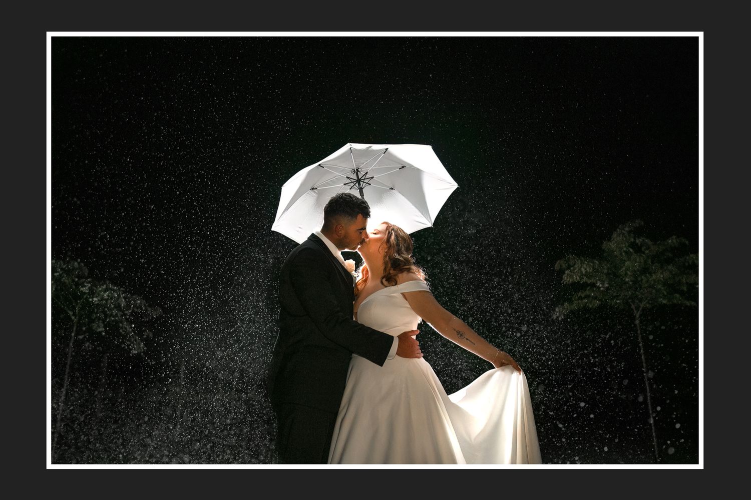A romantic wedding photo captured inside a heart-shaped pendant necklace held by fingertips.