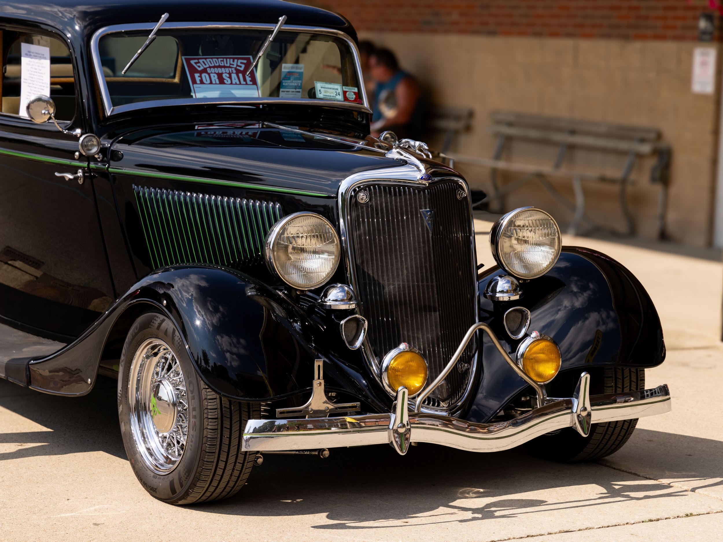 A classic black vintage Ford hot rod with chrome trim parked in sunlight.