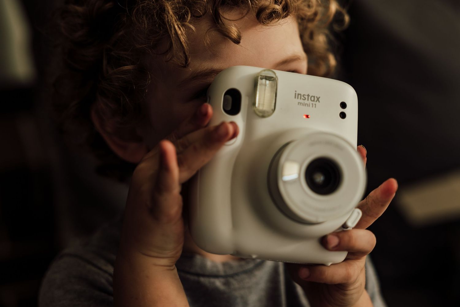 Hands holding white Fujifilm Instax Mini instant camera.