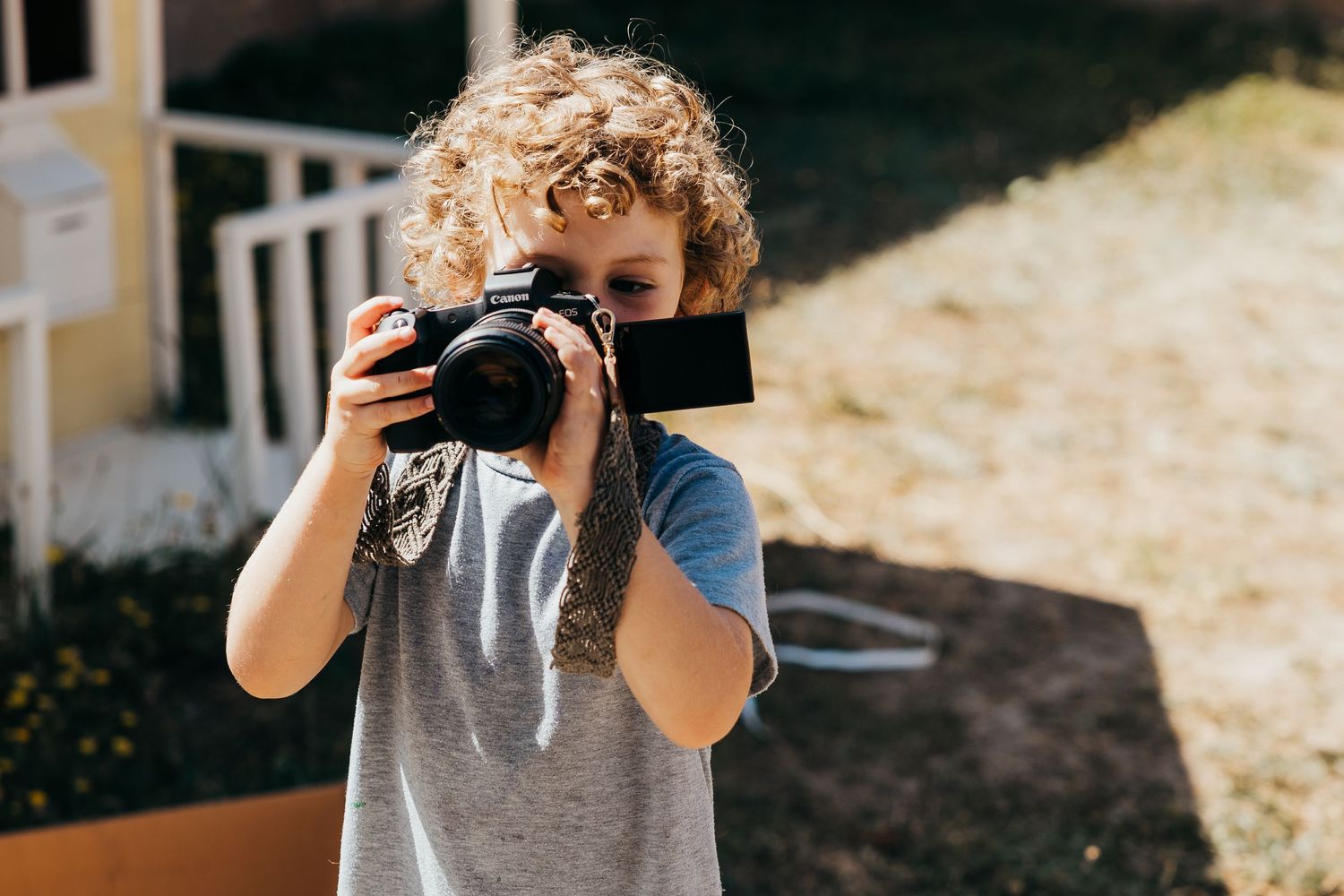 Young photographer holding a professional DSLR camera outdoors on a sunny day.