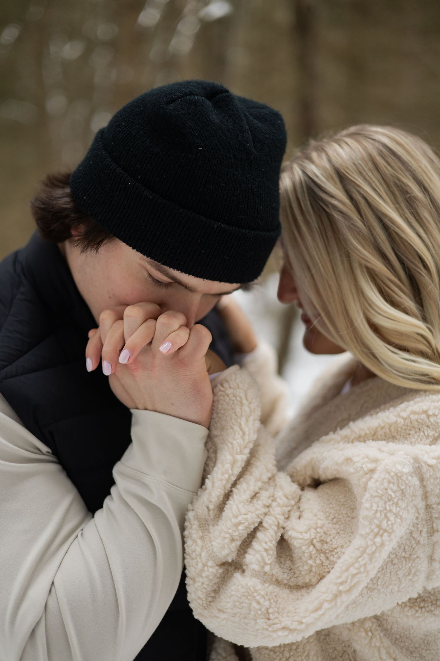 A romantic winter moment showing two people in cozy attire sharing an intimate gesture as one kisses the other's hand.