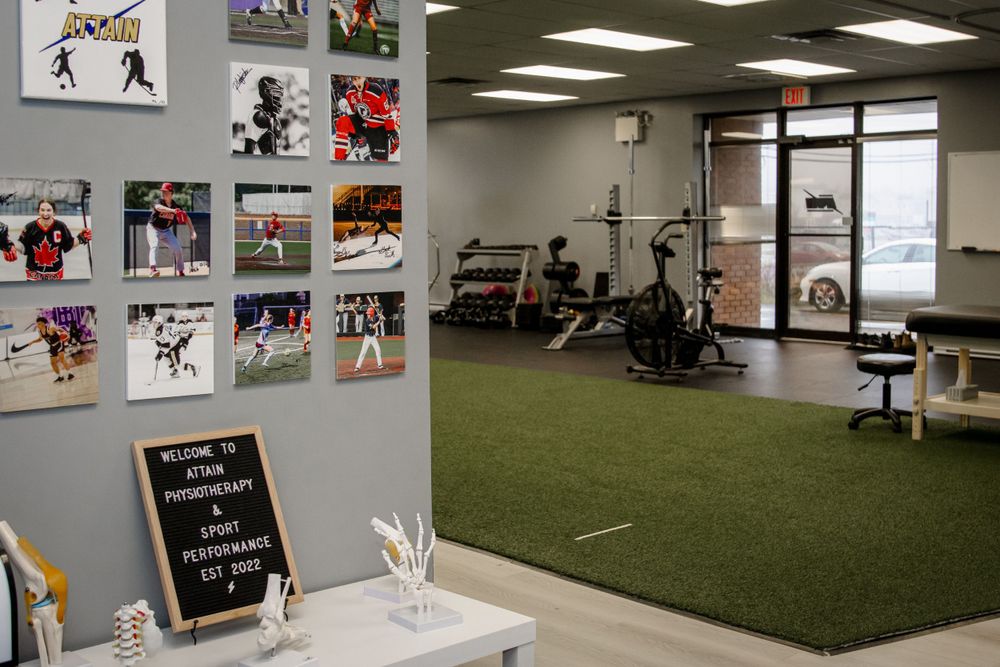 Modern physical therapy or sports training facility with turf flooring, workout equipment and athletic photos on the wall.