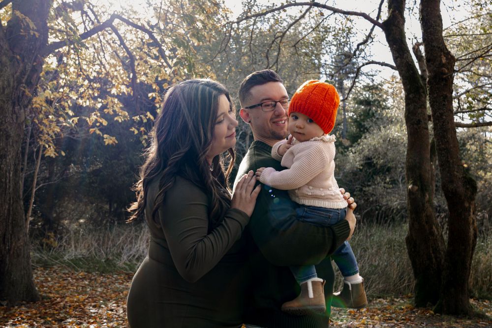A family shares a tender moment together in an autumn forest setting while wearing warm clothing.