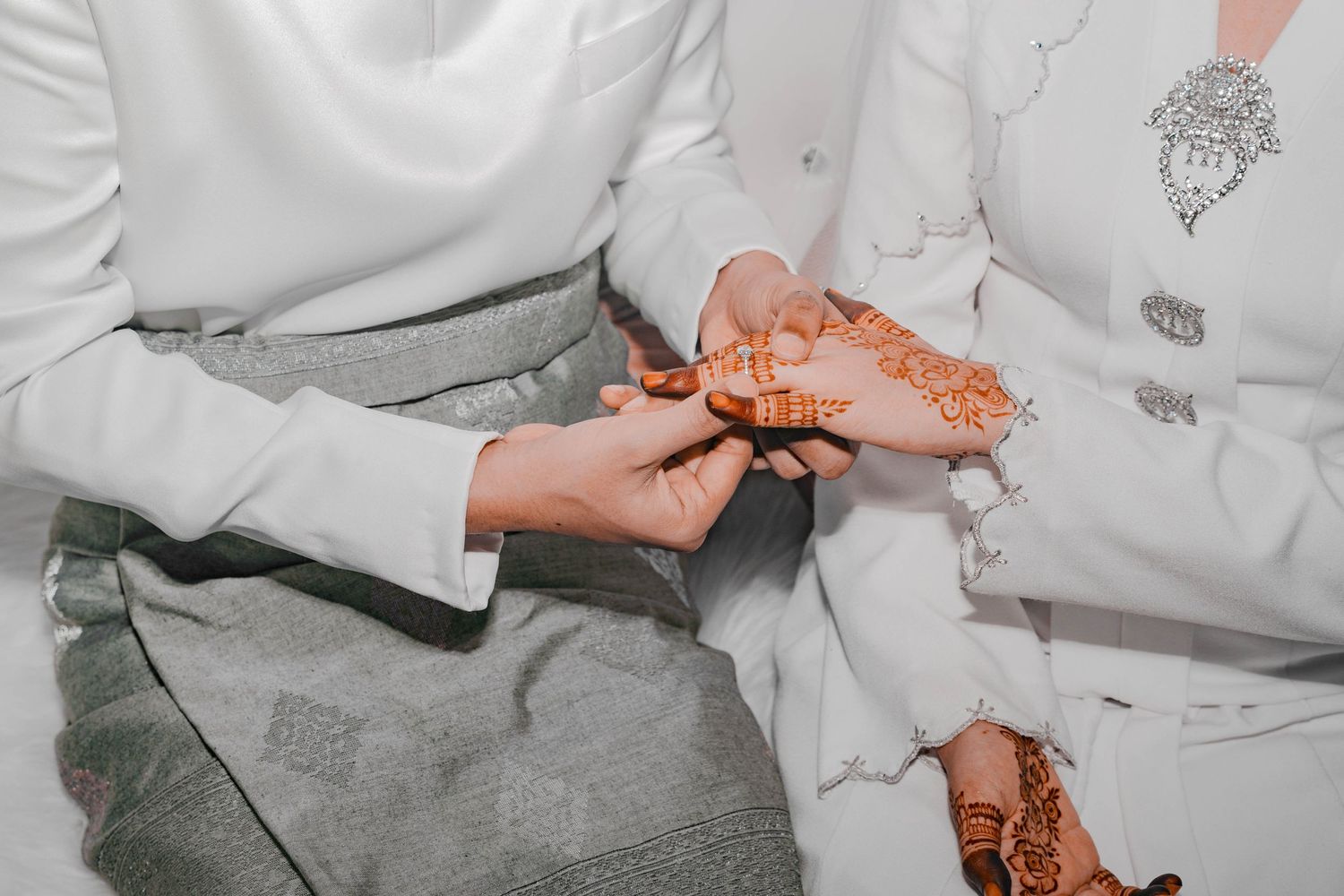 Close-up of hands applying traditional henna designs during a wedding ceremony.