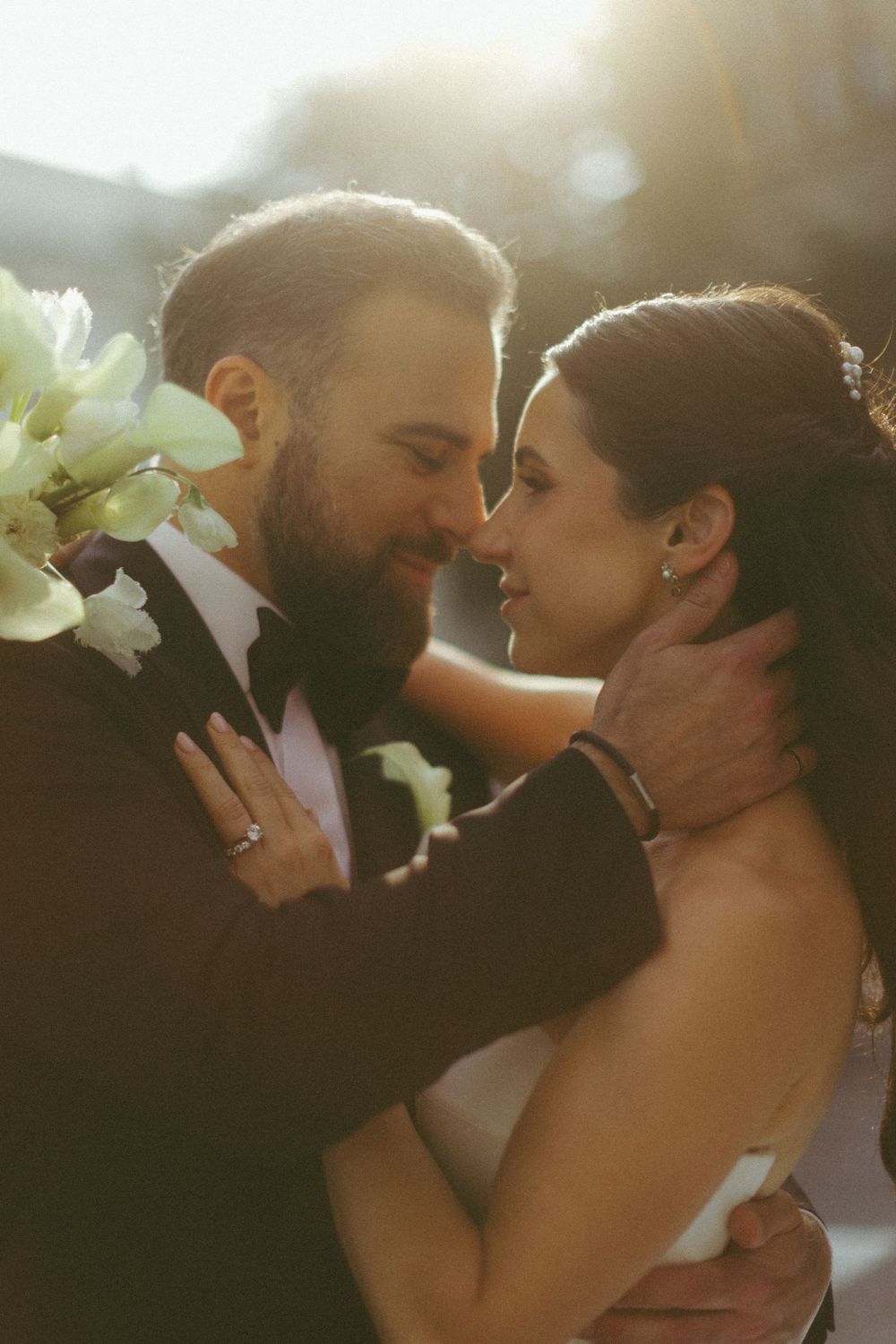 A romantic series of close-up photos showing a couple in warm sunlight with white flowers in their hair.