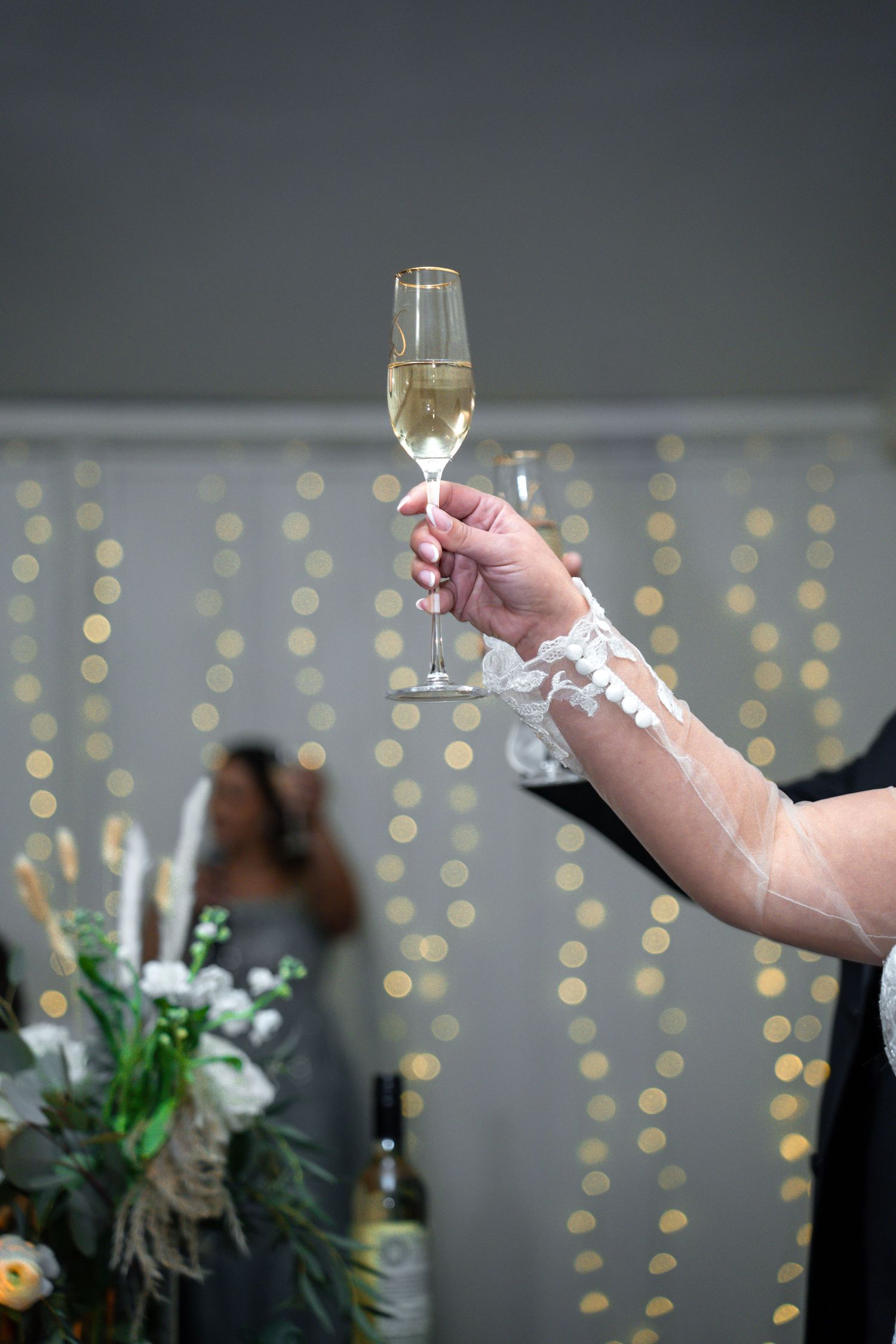 Bride raising a champagne glass in celebration, with soft bokeh lighting in the background.